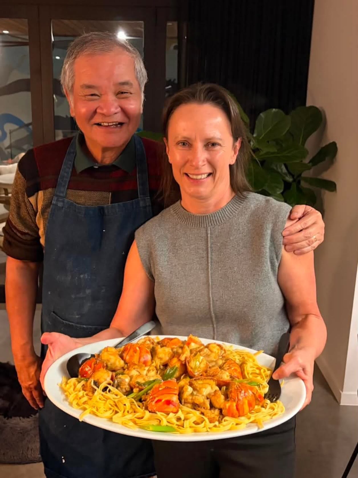 Taste Peddler founder with her mentor Benny, holding a platter of lobster pasta finished with truffle hot sauce
